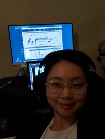 Heather Cui is wearing headphones in front of a monitor showing Applied Systems' technology