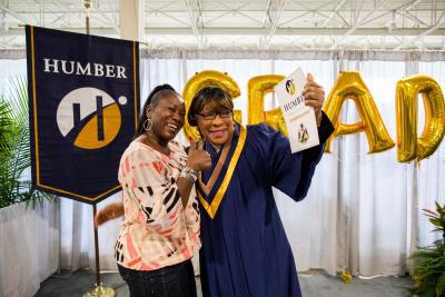 Elmena Walton and her daughter Carole pose joyfully with Carole's diploma and flowers. They are elated.