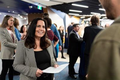 A person holding a piece of paper smiles as they talk with another individual.