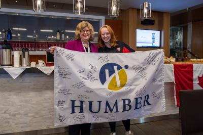 Ann Marie Vaughan and Emma Kilgannon hold a Humber flag with numerous best wishes written on it.