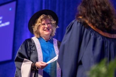 A smiling Ann Marie Vaughan welcomes a Humber College graduate to the stage as part of Fall Convocation.