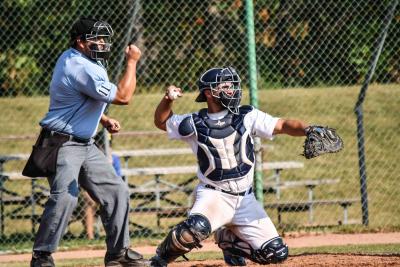 Humber Hawks catcher Justin Marra prepares to throw the ball back to the pitcher while an umpire behind him calls a strike.