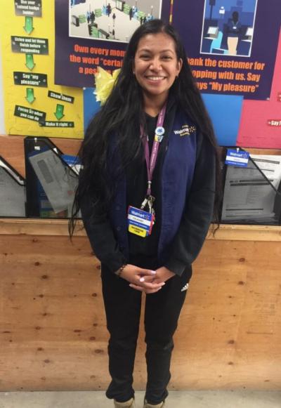 Gajaany Nagulsewaran stands in front of a poster board in a blue sweatshirt, smiling. 