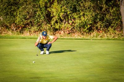 A golfer on the green lines up their putt.