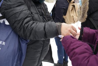 Louise drops seeds into a student's hands. At the end of their walk, they feed the chikadees.