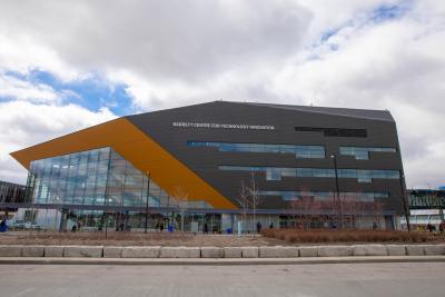 The Barrett CTI is seen across a parking lot. It is a large irregularly-shaped grey building with gold accents