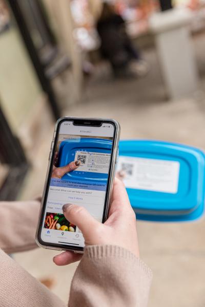 A person uses a smartphone to scan the QR code on a Friendlier reusable food container.