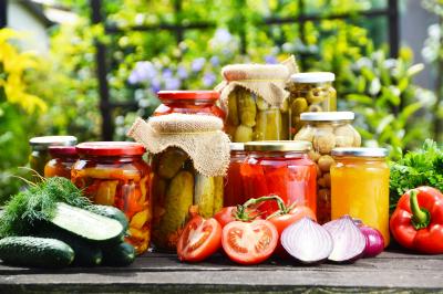 Jars of preserves on a table surrounded by colourful vegetables