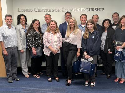 A group of smiling people stand beneath a sign that reads Longo Centre for Entrepreneurship.