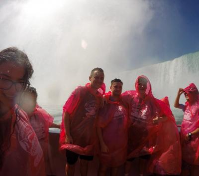 Several people wearing rain jackets pose for a photo with Niagara Falls in the background.