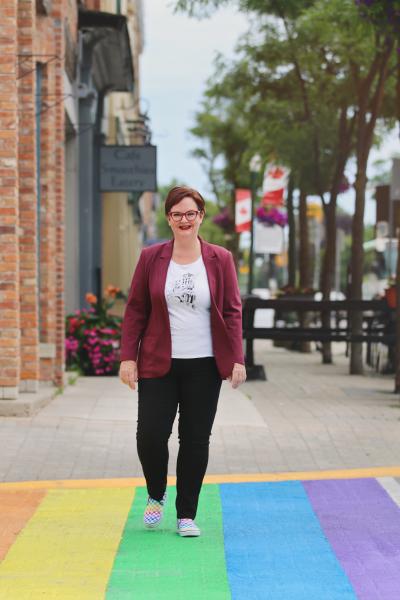 Orangeville town Councillor Lisa Post walks across a rainbow-coloured crosswalk