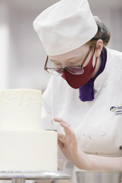 Emma Kilgannon in her chef’s uniform decorating a cake.