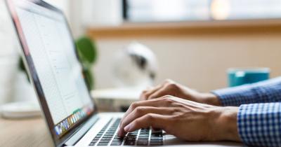 Two hands type on a laptop computer.