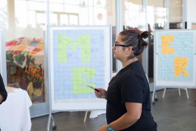 students look at big boards of sticky notes, pens in hand