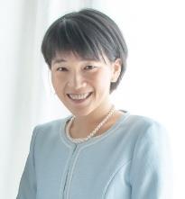 Kayoko Ochi smiles at the camera, wearing a light blue sweater