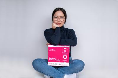 Oat Canada co-founder Eloise Ambursley sits cross legged with a pink box of oat milk on her lap