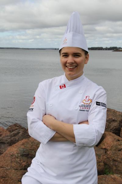 Stefanie Francavilla stands on shore in PEI in her chef whites